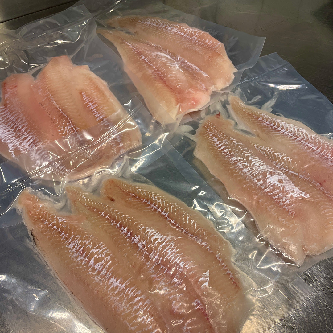 Fotot på handskurna koljafiléer på rostfri köksbänk