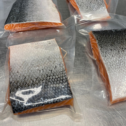 Fyra vakuumförpackade laxfilebitar på rostfri köksbänk